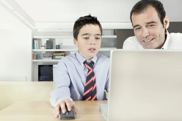 Pai ajudando filho a fazer sua lição de casa em um computador portátil em casa . — Fotografia de Stock