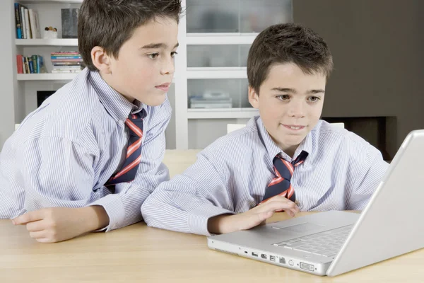 Twee tweelingbroers een laptopcomputer thuis delen. — Stockfoto
