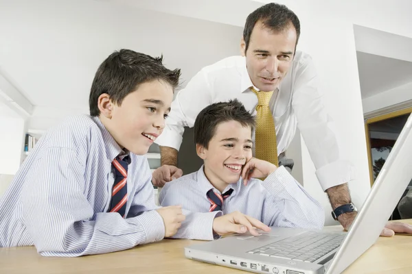 Pai e filhos usando um computador portátil em casa . — Fotografia de Stock