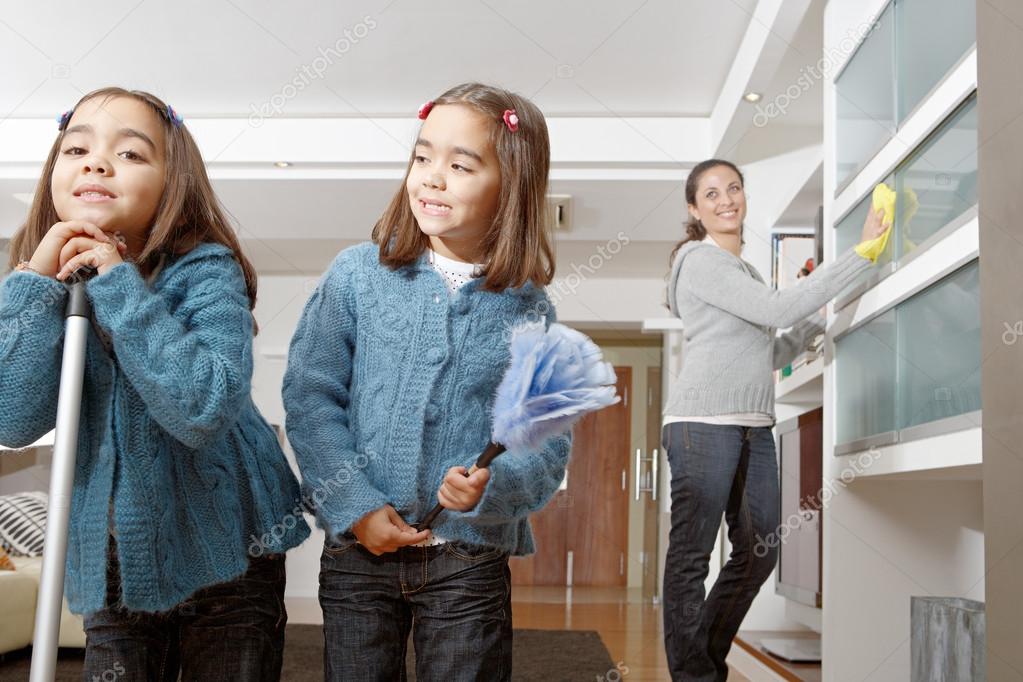 Two identical twin sisters cleaning their home living room while on