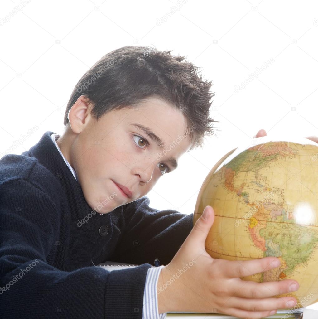Young boy using a world .globe to learn geography while doing his homework near a window