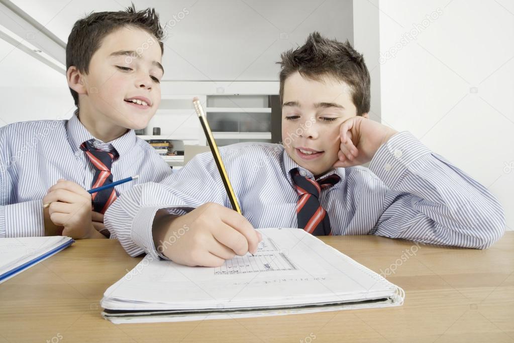 Two brother playing games while doing homework at home.