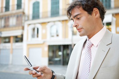 bir cep telefonu kullanarak bir genç çekici işadamı bir Avrupa şehri ile klasik ofis binaları arka planda portresi.