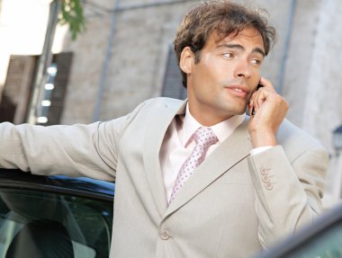 şehir içinde araba tarafından duran bir telefon görüşmesi yapmak için bir cep telefonu kullanarak iş adamı.