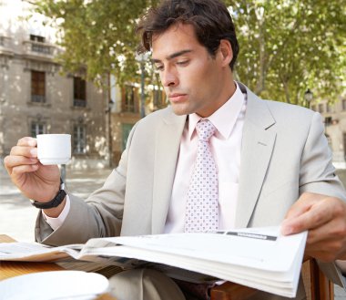 işadamı bir kafe teras kahve yudumlarken gazete okuma