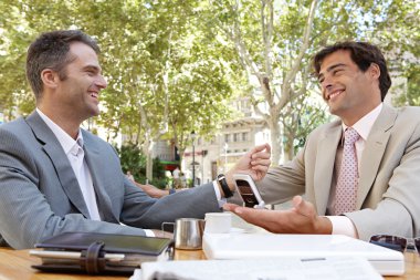 Two businessmen having a meeting in a coffee shop terrace outdoors. clipart