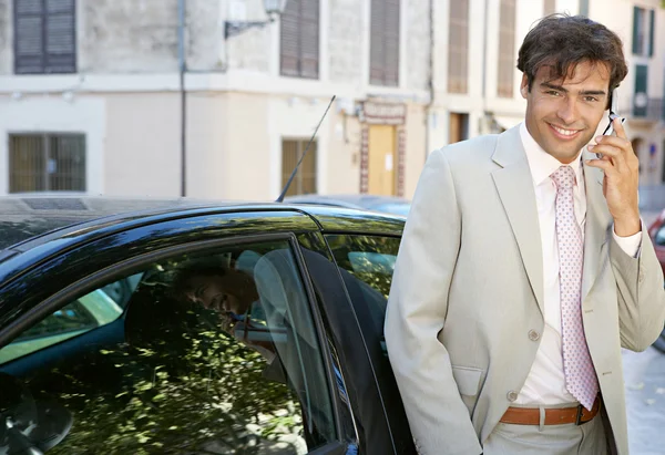 Бізнесмен, використовуючи мобільний телефон, щоб зробити телефонний дзвінок, стоячи на машині в місті . — стокове фото