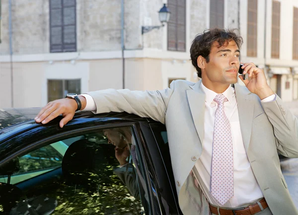 şehirde bir araba ile duran bir telefon görüşmesi yapmak için bir cep telefonu kullanarak iş adamı.