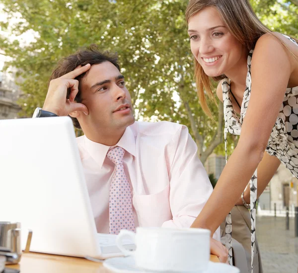Homme d'affaires et femme d'affaires utilisant un ordinateur portable tandis que dans un café table de terrasse à l'extérieur dans une ville classique . — Photo