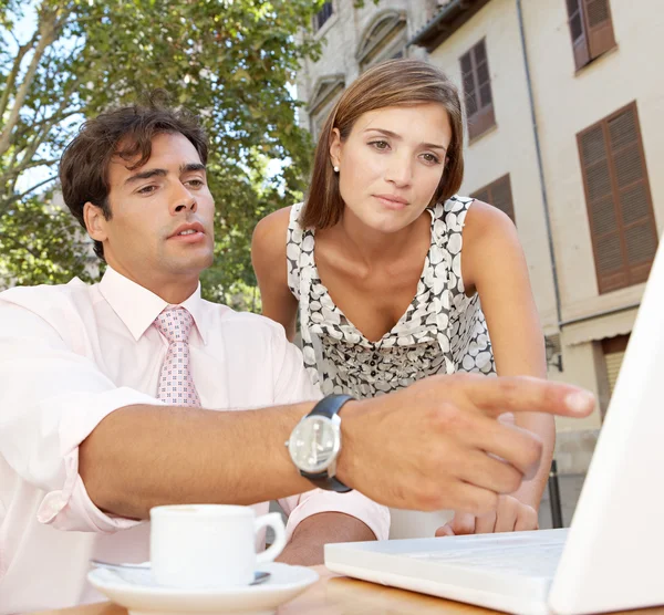 Business colleagues looking at a laptop screen while having a meeting in a coffee shop terrace — Stock Photo, Image