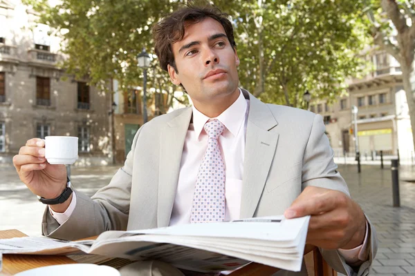 Businessman reading the newspaper while having a coffee in a coffee shop terrace — Stock Photo, Image