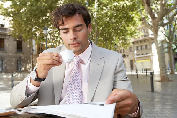 Biznesmen czytanie gazety podczas picia kawy na tarasie kawiarni — Zdjęcie stockowe