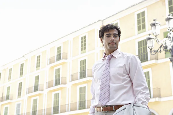 Jovem empresário hispânico em pé em frente a um prédio de escritórios uniforme, ao ar livre . — Fotografia de Stock
