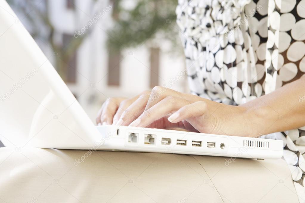 Close up of a busineswoman's hands typing on a laptop computer outdoors.