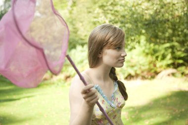 ormanda bir kelebek ağı tutan genç kız.