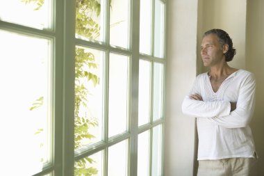 güneşli bir gün içine büyük bir pencere profesyonel olgun adam evde bakarak.