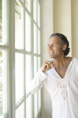 güneşli bir gün içine büyük bir pencere profesyonel olgun adam evde bakarak.