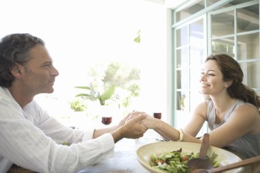 Olgun çift onların tatil evinde öğle yemeği sırasında elele.