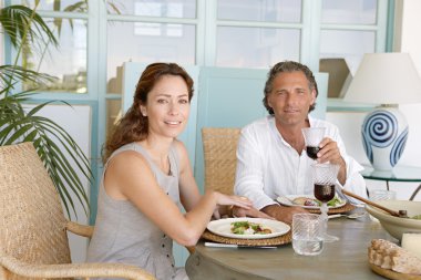 Olgun çift yemek ve birlikte Bahçe masada, kameraya gülümseyen içme.