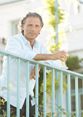 Olgun erkek iken bir balkonda eğilerek şampanya içmek.