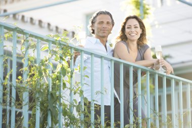 Olgun çift açık havada bir otelin balkonunda süre eğilerek şampanya içmek.