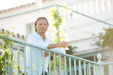 Olgun erkek iken bir balkonda eğilerek şampanya içmek.