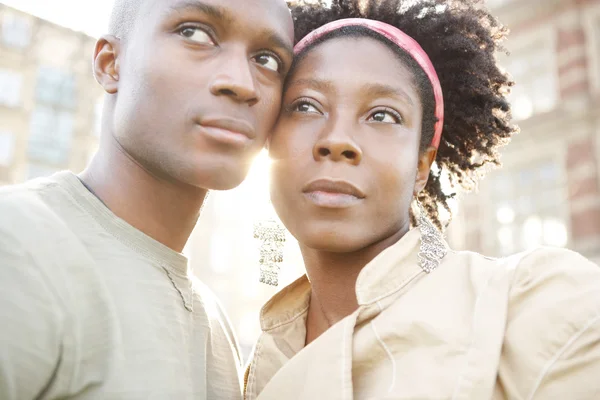 Retrato de una joven pareja negra de turistas visitando la ciudad al atardecer, holidng sus cabezas juntas . — Foto de Stock