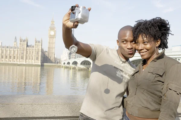 Tourist couple taking a picture of themselves while visiting Big Ben in London city. — Stock Photo, Image