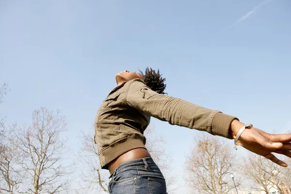 Atractiva mujer negra expresando libertad contra un cielo azul intenso —  Fotos de Stock