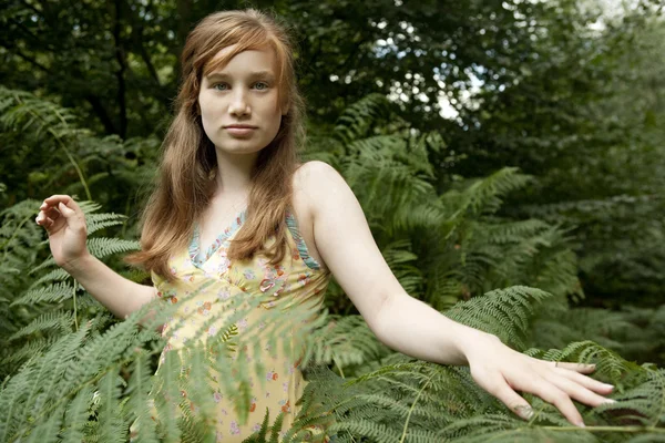 Tonårig flicka gå genom skogen fern lämnar. — Stockfoto