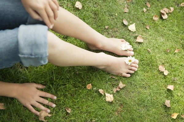 Vista aérea de las piernas y los pies de la joven, con flores entre los dedos de los pies . — Foto de Stock