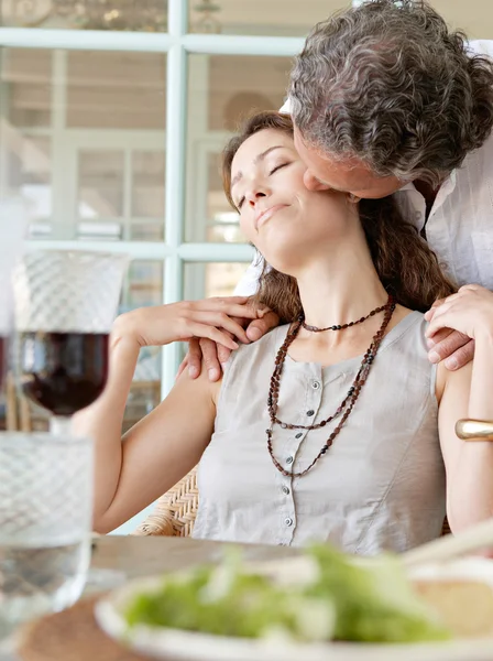 Olgun erkek kadın sağlıklı yemek masasında, açık havada oturma sırasında kissing. — Stok fotoğraf