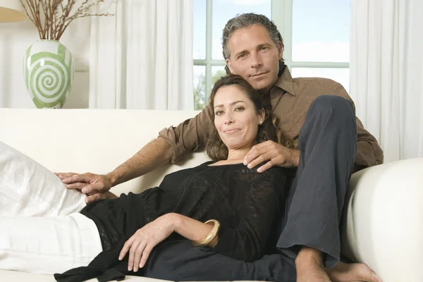 Portrait of a mature couple lounging on a sofa at home and holding hands. — Stock Photo, Image