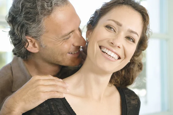 Volwassen man en vrouw knuffelen en in elkaars thuis oor fluisteren. — Stockfoto