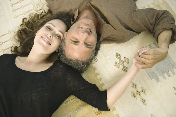 Over head portrait of a mature man and woman laying down on carpet — Stock Photo, Image