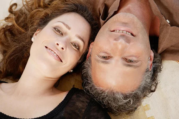 Nad głową widok starsza para, ustanawiające na dywanie w domu, uśmiechając się. — Zdjęcie stockowe