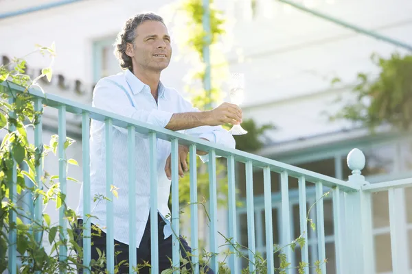 Olgun adam açık havada bir balkon eğilir gibi şampanya holding.