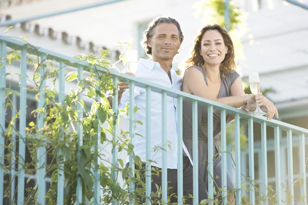 Olgun çift açık havada bir otelin balkonunda süre eğilerek şampanya içmek.