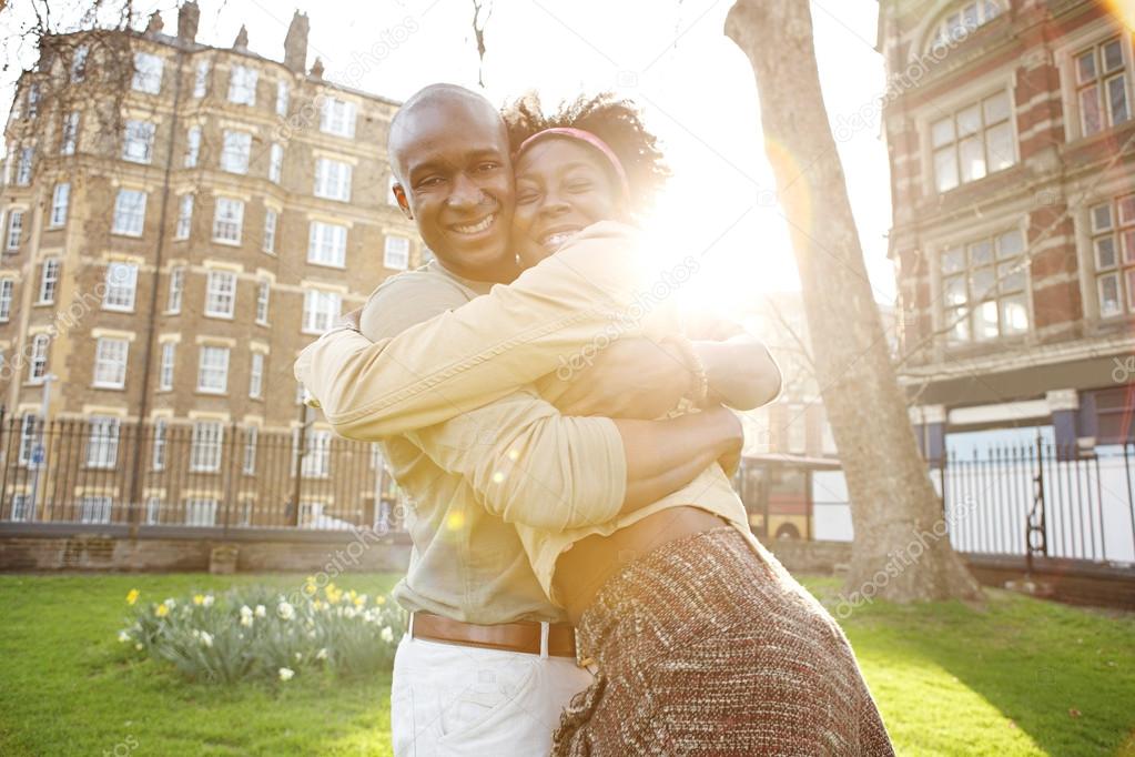 Young black tousits couple passionately hugging in a park, laughing and having fun.