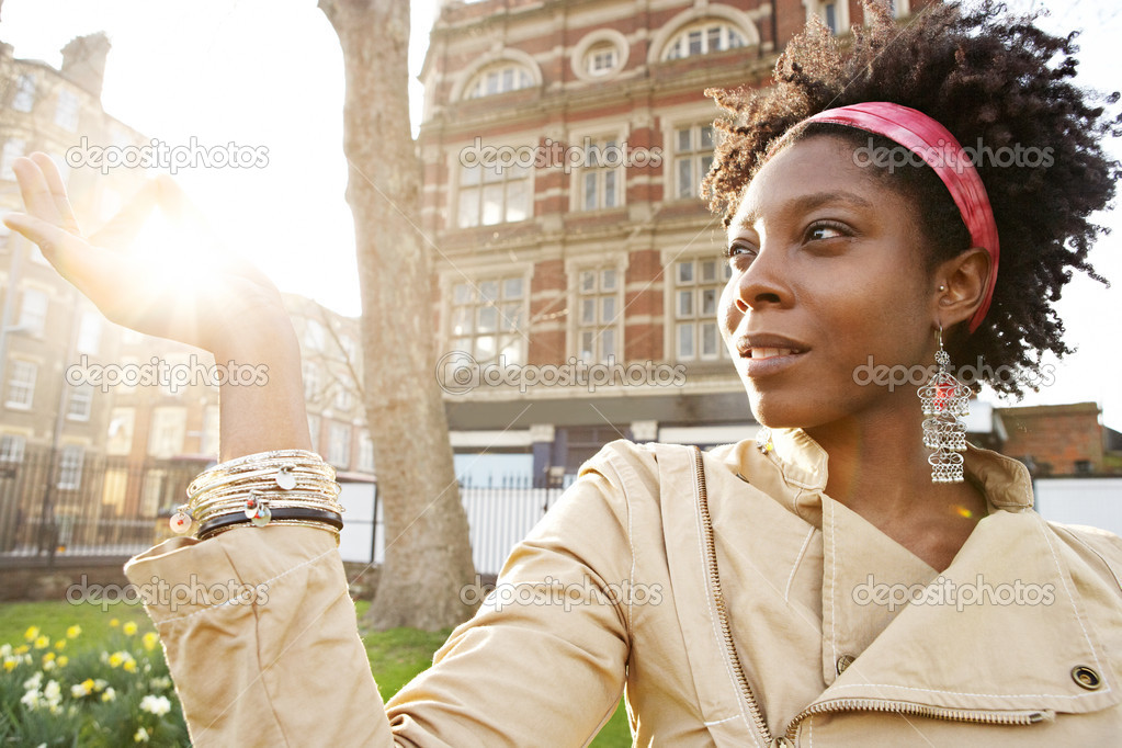 young black woman holding the sun between her fingers at sunset