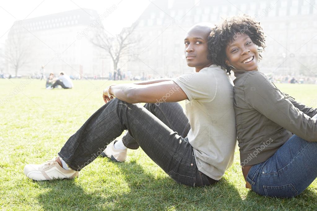 Young african american couple sitting back to back while visiting London on vacation