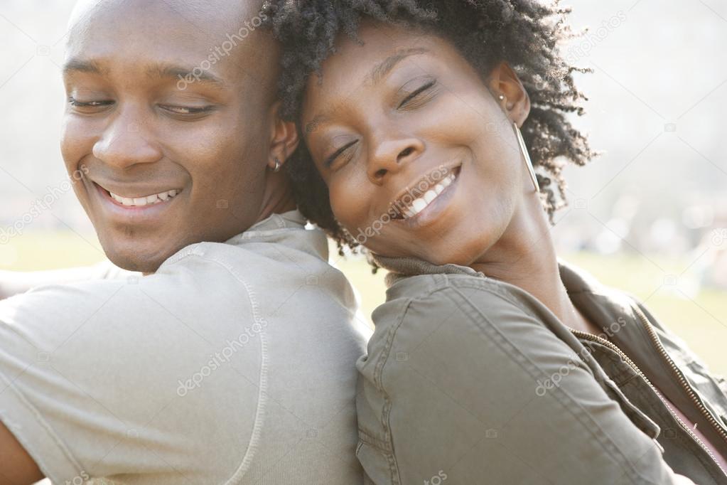 Young african american couple sitting back to back while visiting London on vacation