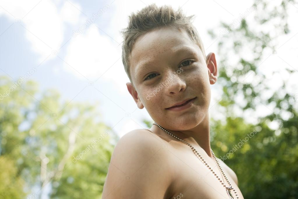 Side view of teenage boy smiling at camera, outdoors.