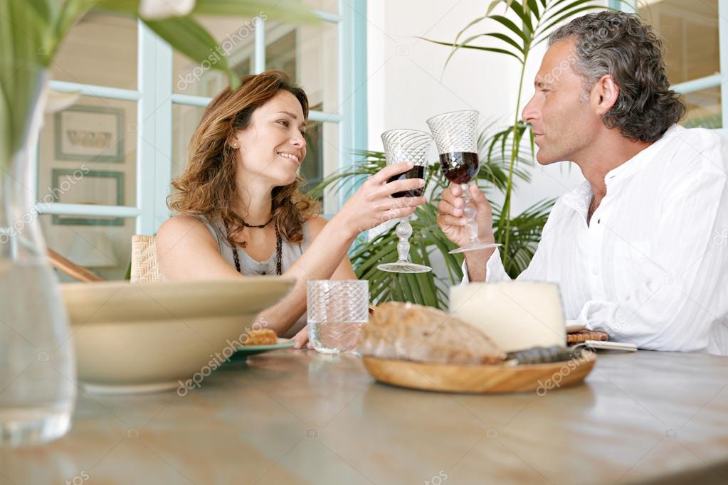 Mature cople toasting with red wine while having healthy lunch outdoors.