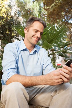 bir klasik şehir parkta bir bankta otururken bir smartphone kullanarak üst düzey iş adamı