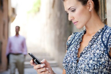 Klasik şehir Sokak merdivenleri ile duran bir akıllı telefon kullanan genç iş kadını.