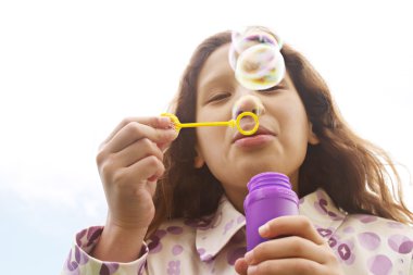 baloncuklar gökyüzüne karşı esen genç kız gülümseyerek.