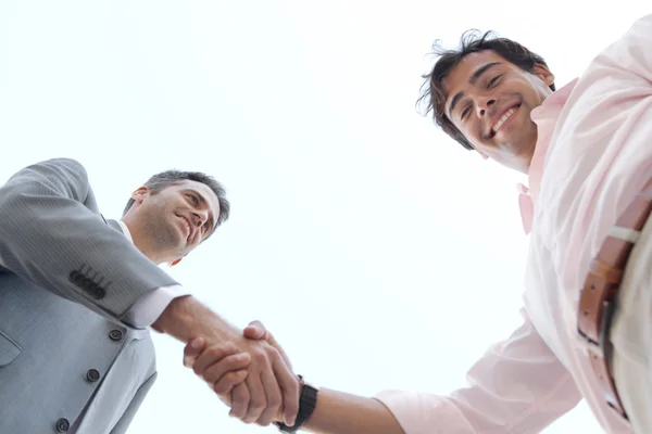 En vue de deux hommes d'affaires serrant la main à nouveau le ciel . — Photo