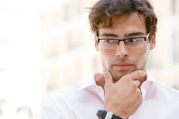 Homem de negócios atraente sendo pensativo enquanto está ao lado de edifícios de escritórios — Fotografia de Stock