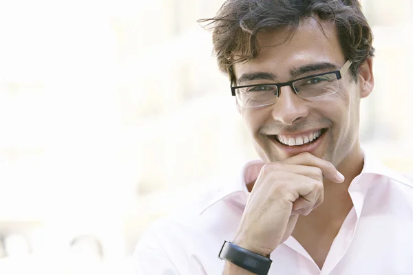 Retrato de un joven empresario sonriendo a la cámara, sosteniendo la barbilla con la mano . — Foto de Stock